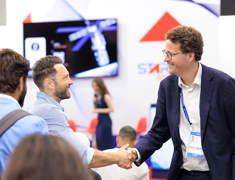 Deux professionnels se serrent la main sur un stand d’exposition lors du Salon International de l’Aéronautique et de l’Espace à Paris-Le Bourget.