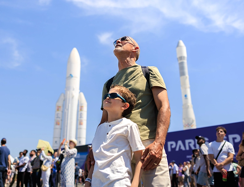 Un adulte et un enfant regardent les démonstrations aériennes lors du Salon International de l’Aéronautique et de l’Espace à Paris-Le Bourget.