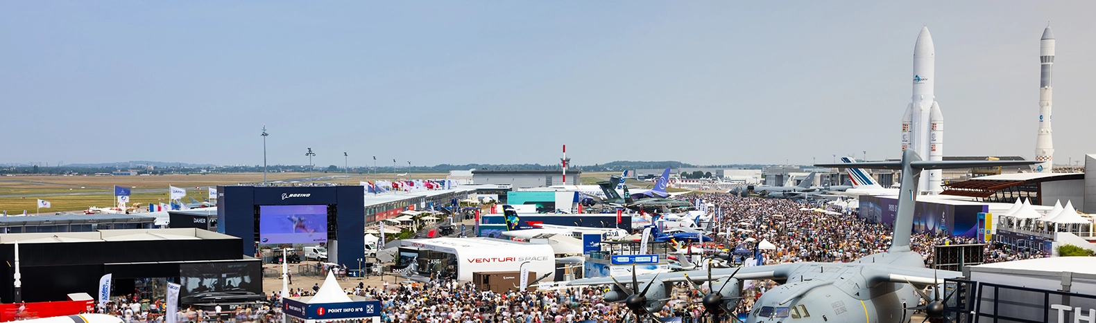 Vue panoramique du Salon International de l’Aéronautique et de l’Espace avec aéronefs exposés, stands des industriels et visiteurs à Paris-Le Bourget.